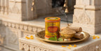 Candle labeled 'Maharaja Chandan' on a decorative tray with sandalwood and other items in front of an architectural background.