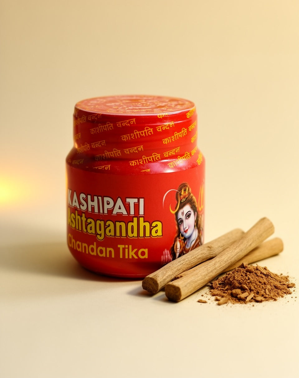 Red container of Kashipati Chandan Tika with two sticks and some powder on a beige background
