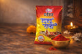 Packaged spice product with a bowl of red powder on a wooden surface.