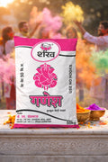Bag of Shani Ganesh color powder with people celebrating Holi in the background