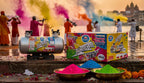 Colorful powder cans and holi colors with people in the background at sunset.