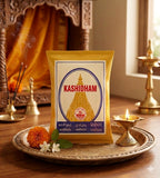 Kashidham package on a decorative plate with flowers and a lit candle in a warm setting
