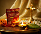 Shankh Puja Chalo packet with a lit candle and decorative elements on a wooden surface.