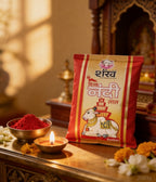 Kumkum packet with red powder and lit candle on a decorative surface