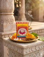 Vermilion powder packaging on a decorative platter with flowers and incense, set against a stone architectural background.