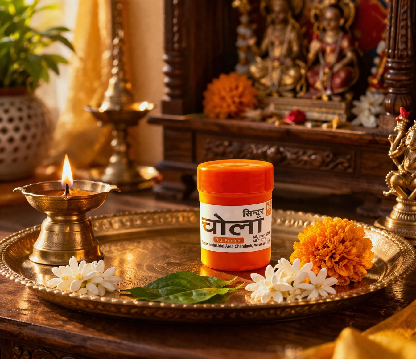 Container of Chandan (sandalwood) on a decorative tray with flowers and a lit lamp in a traditional setting.