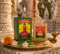 Lakshmi vermillion packaging on a decorative tray with flowers and incense in front of temple architecture.