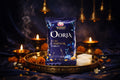 Shankh Oorja Pure Camphor Tablet packaging on a dark background with candles and flowers.