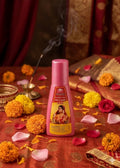 Pink bottle with a colorful label on a decorative background with flowers and candles.