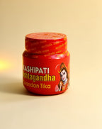 Red container of Kashipati Chandan Tika on a beige background