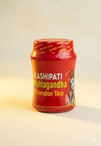 Red container of Kashipati Chandan Tika on a light background