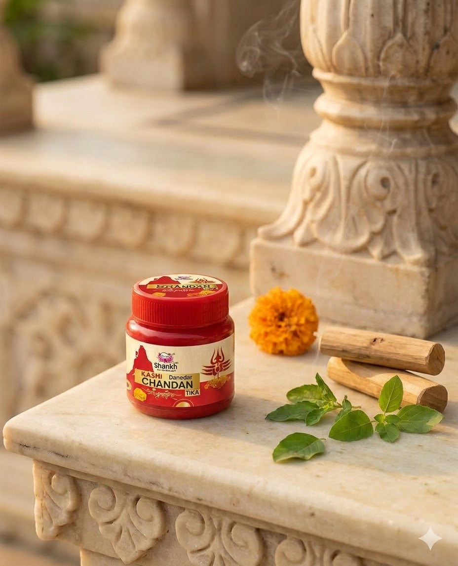 Jar of Chandan incense on a decorative stone surface with marigold flowers and sticks.