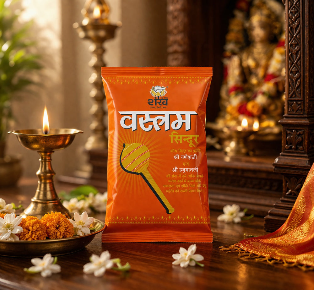 Orange packet of Vatsam Sindhu on a wooden surface with decorative items in the background